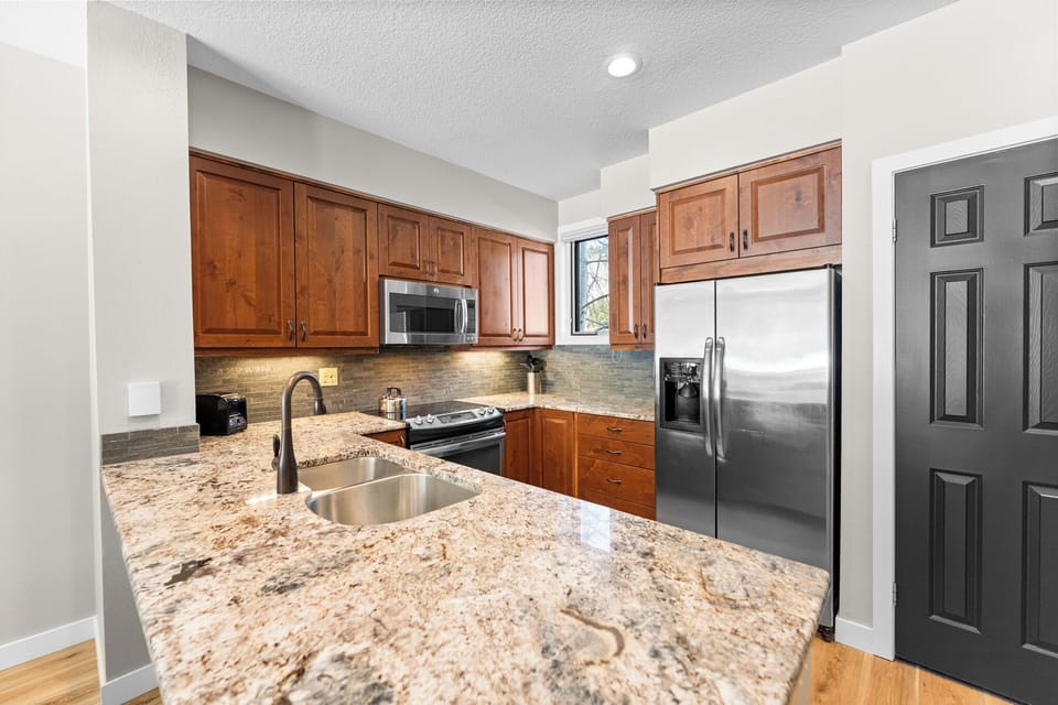 Cook your favorite meals in this fully equipped kitchen featuring granite countertops, rich cherry cabinets, and stainless steel appliances for your culinary adventures.