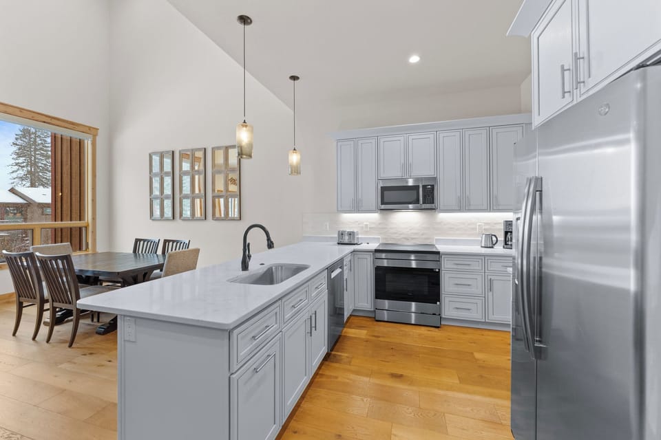 Cook memorable meals in this sleek modern kitchen featuring stainless steel appliances, granite countertops, and elegant pendant lighting—perfect for your vacation dining.