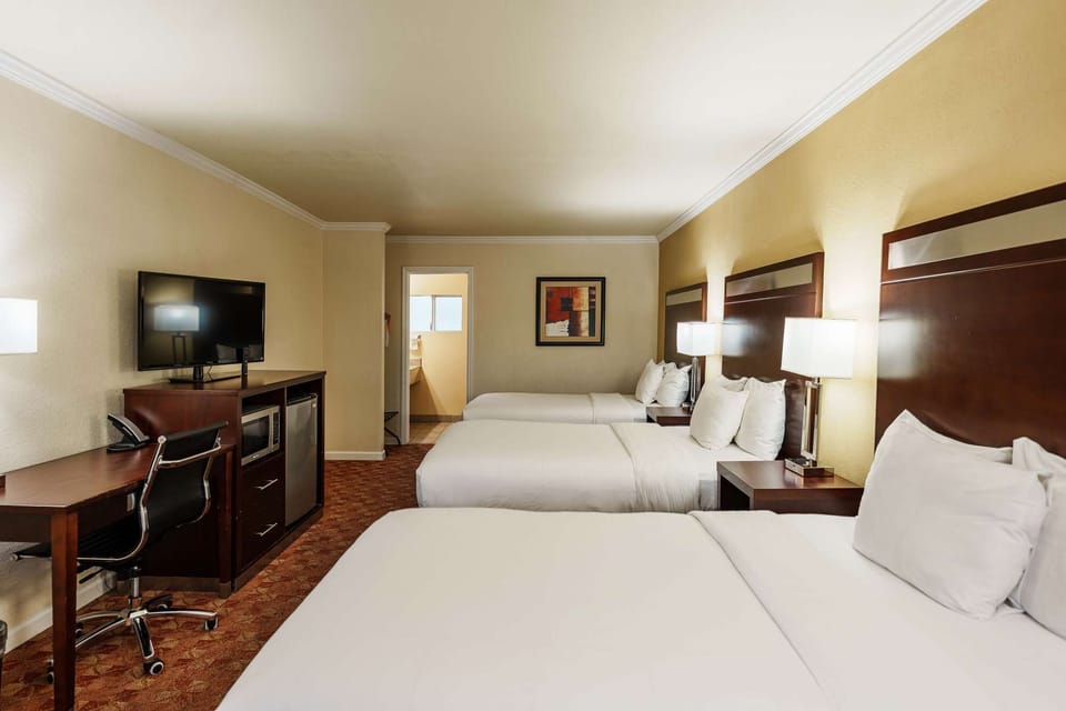 Spacious room with three comfy beds, desk, TV, and warm lighting