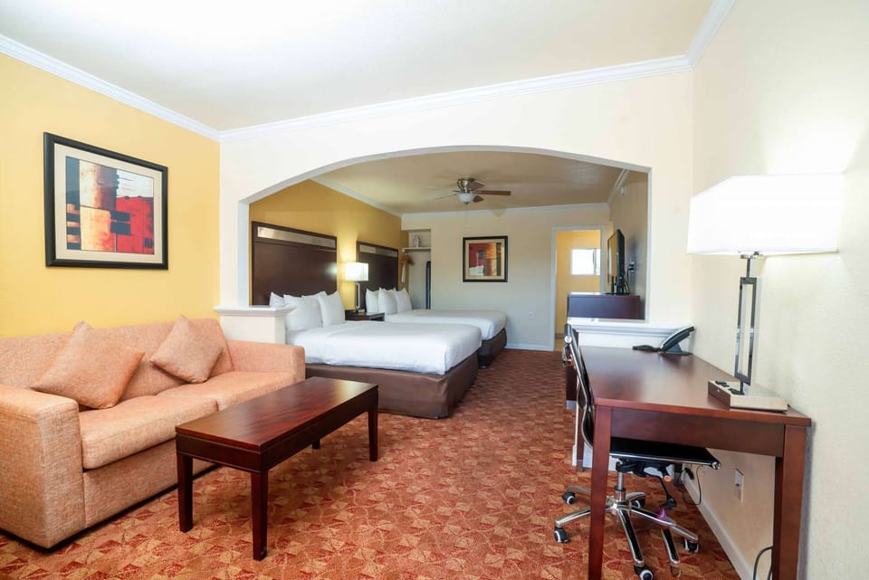 Large room with sofa, two beds, and work desk in warm tones