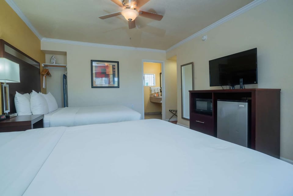 Comfortable beds, ceiling fan, TV, and open bathroom area