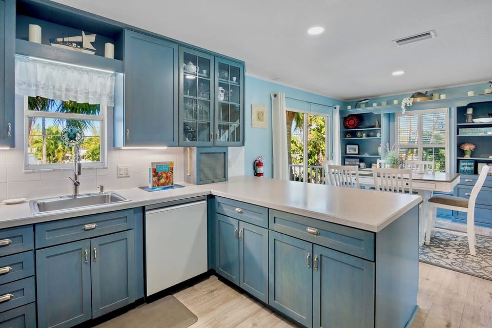 Your coastal-inspired kitchen awaits with sea-blue cabinetry and tropical views that make meal prep feel like vacation living.
