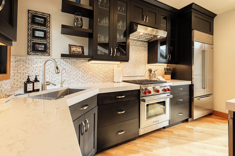Wide kitchen view with dark cabinets, stainless appliances, and bright counters.