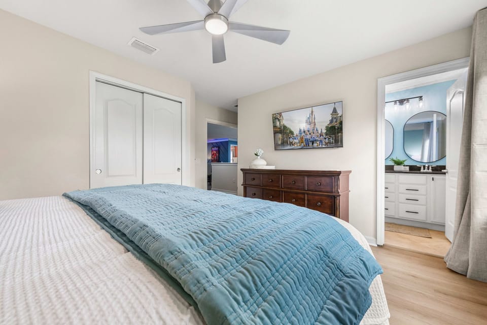 Spacious king bedroom with wall-mounted smart TV, LED ceiling fan, and private ensuite bath.
