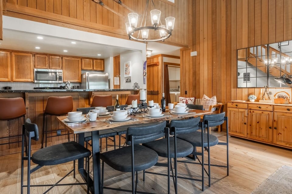 Gather around the inviting dining table under warm pendant lighting, with the open kitchen just steps away. Rich wood tones and vaulted ceilings create a cozy mountain retreat where meals and memories come together effortlessly.