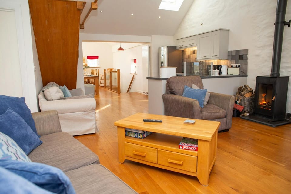 Open-plan living room with sofas, wooden coffee table and log burner