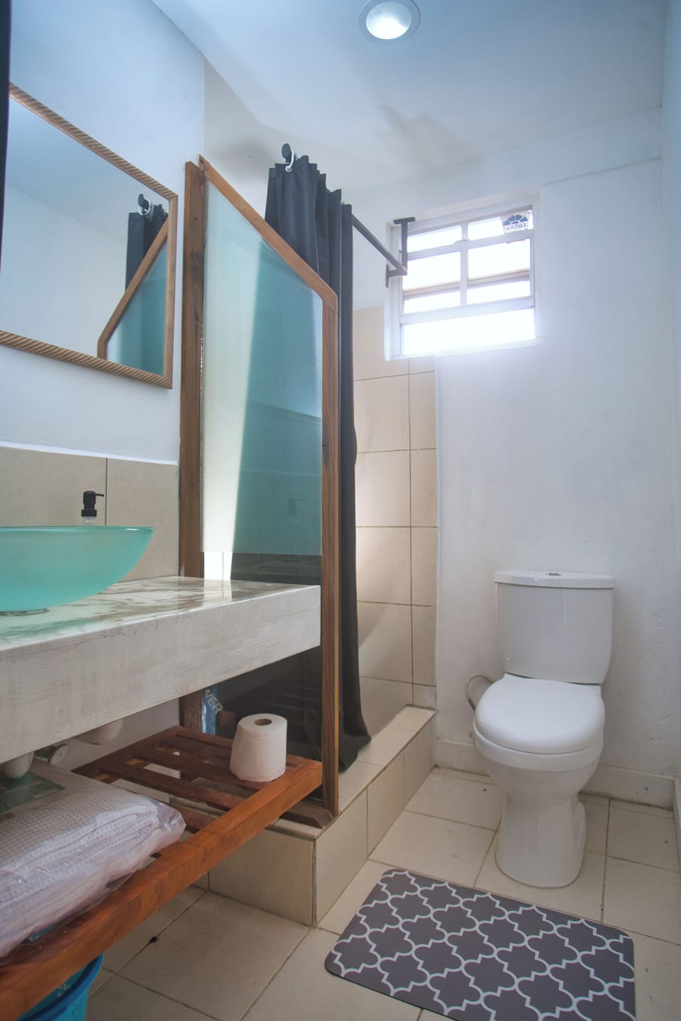 Clean, modern bathroom with a glass sink and warm tile shower.