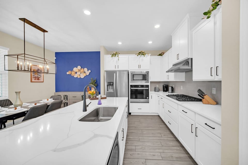 Modern kitchen with white cabinetry, stainless steel appliances, and a spacious island for cooking and dining.
