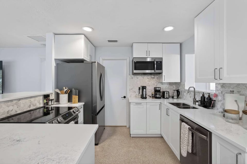 Modern, fully equipped kitchen with marble backsplash, stainless steel appliances, and a dedicated coffee station featuring two espresso machines for cappuccinos. Bright, clean, and comfortable, ideal for extended stays and remote work.