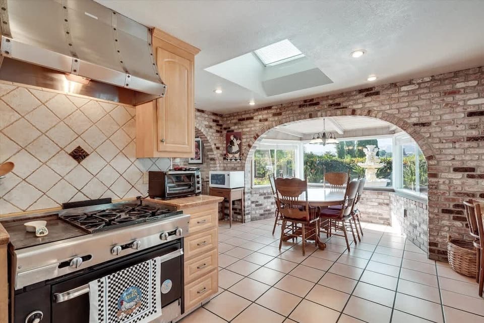 Sunlit kitchen with rustic brick and cozy dining nook