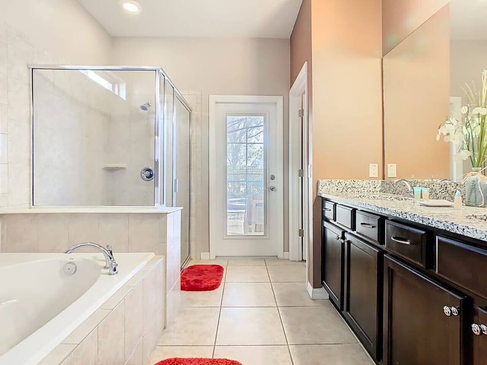 Primary bathroom featuring a soaking tub, walk-in shower, and direct outdoor access.