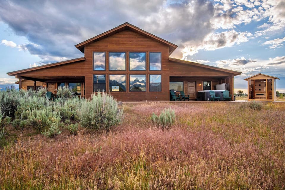 Sagebrush wildflowers frame the home's façade as the Tetons rise in the distance — the view that greets you every time you arrive