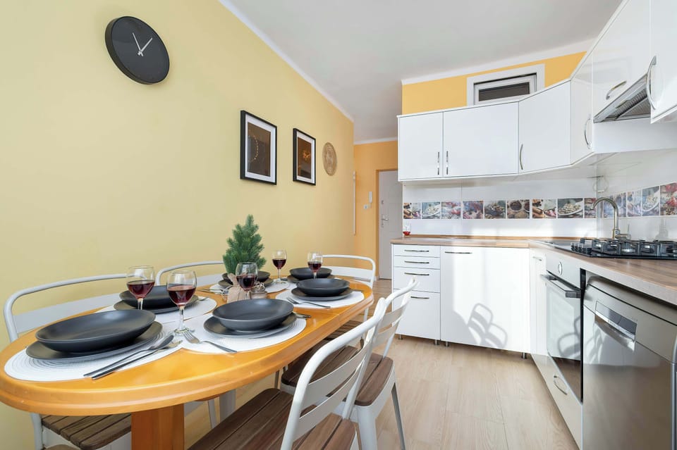 Another dining view showing the table placed near the kitchen. The arrangement feels functional and cozy. Light colors dominate the space.