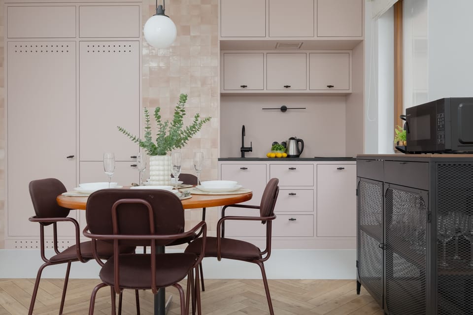 Elegant dining area with wooden table and minimalist kitchen in the background.