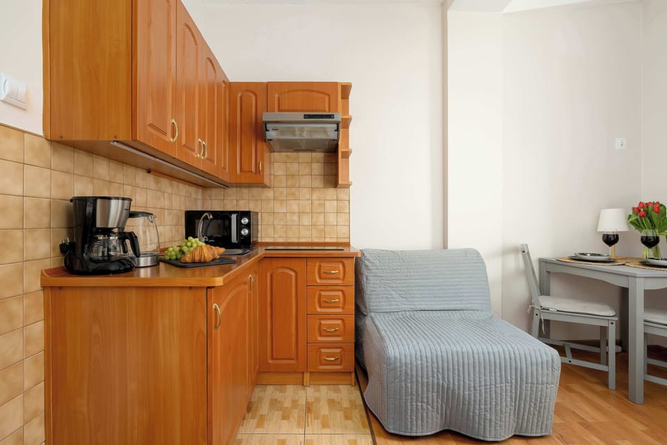 A kitchen area with upper and lower wooden cupboards, integrated appliances, and a small seating nook nearby.