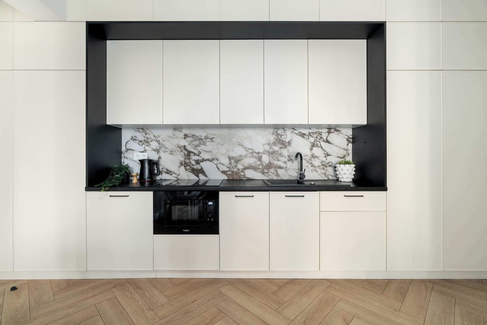 Modern kitchen with built-in appliances, marble-style backsplash, and sleek cabinetry.