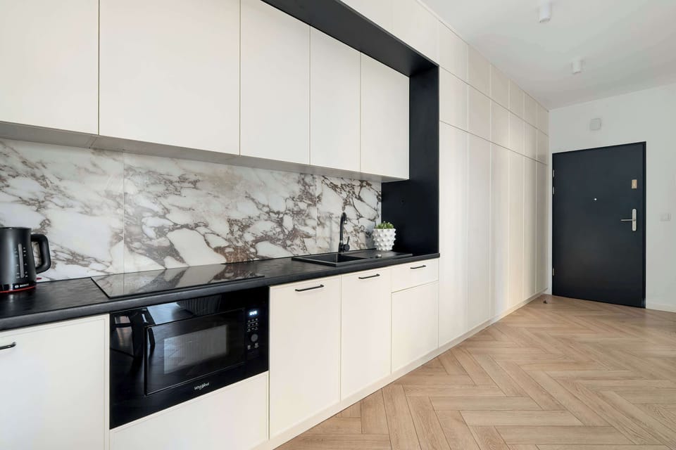Modern kitchen with built-in appliances, marble-style backsplash, and sleek cabinetry.