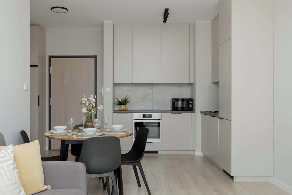 A kitchen and dining corner showing a small table placed next to the cooking area. The layout maximizes space efficiently. Light tones keep the room bright.