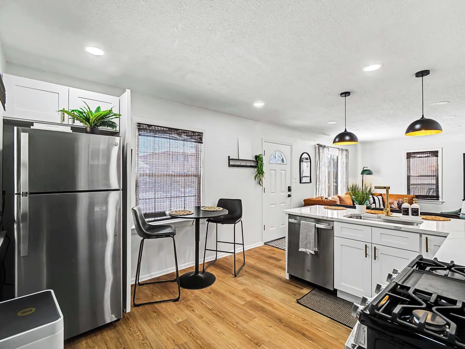 Sleek kitchen w/ stainless steel fridge, bar stools & bright windows bringing in natural light