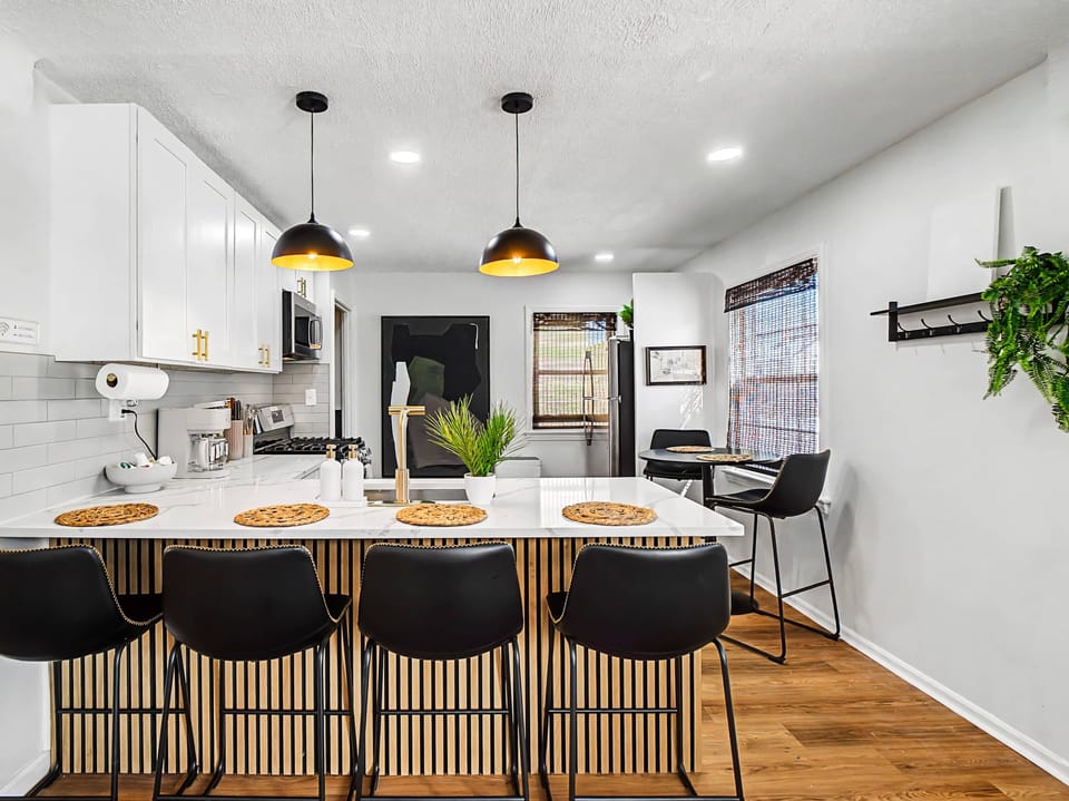 Modern kitchen island w/ bar seating under warm pendant lights, great for meals & gathering together