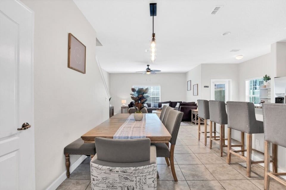 A dining area with a long table, contemporary lighting, and seating for the whole family.