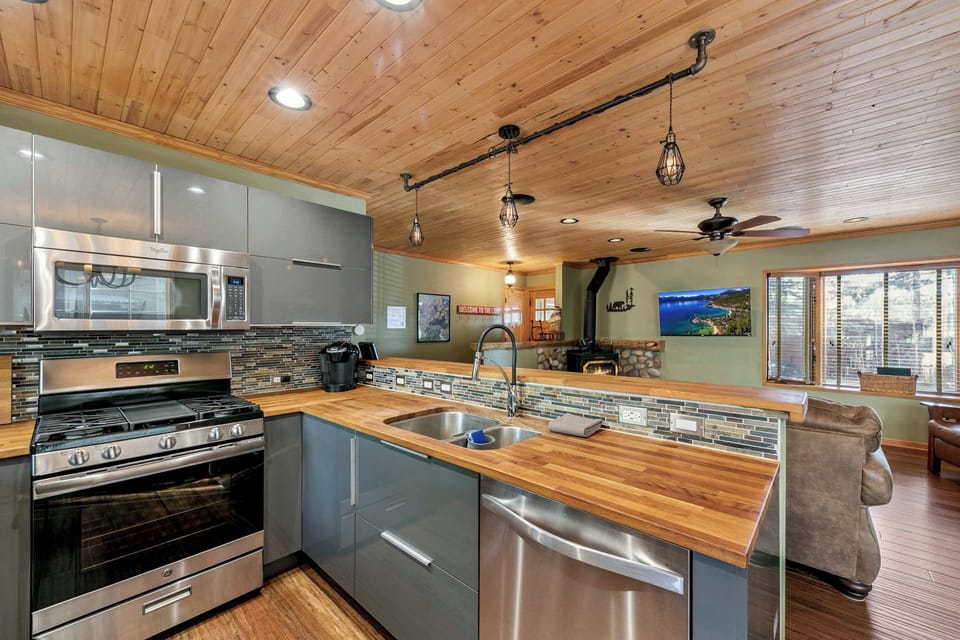 Open-concept kitchen with warm wood ceilings and modern appliances—cook, dine, and relax together in this inviting gathering space.
