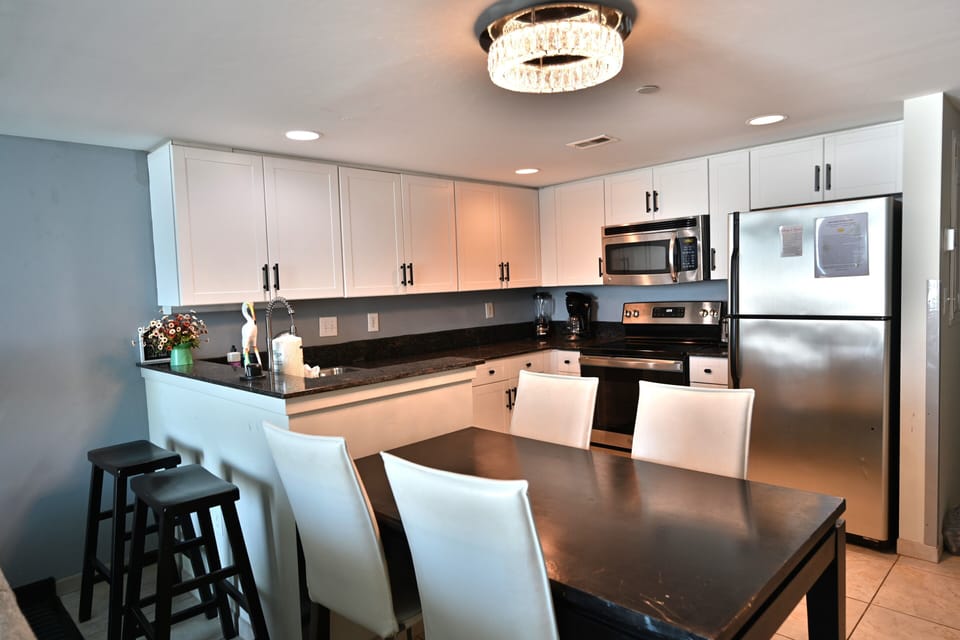 Bright kitchen with bar seating, dining table, and chic lighting.