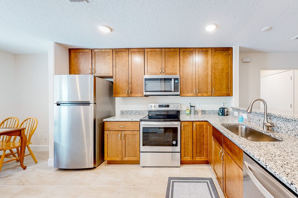 The kitchen extends across the bar top to the living room and has all stainless steel appliances including fridge, microwave, oven, stove, and dishwasher.