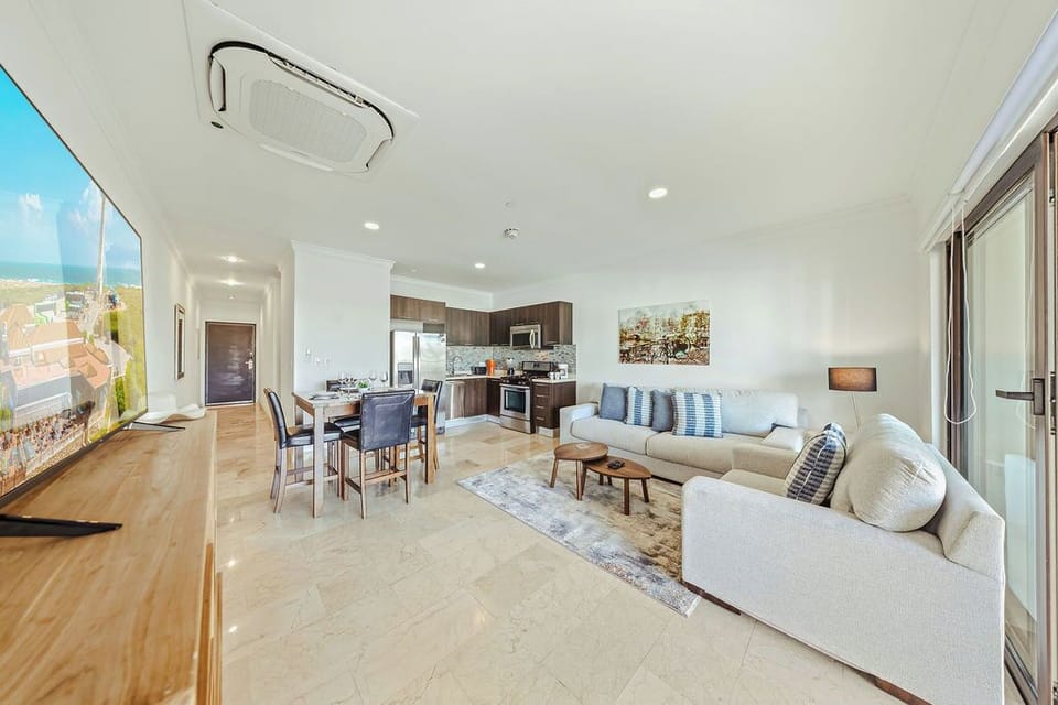 Spacious open-concept living area with cozy seating, a full kitchen, and direct access to the balcony for indoor-outdoor relaxation.