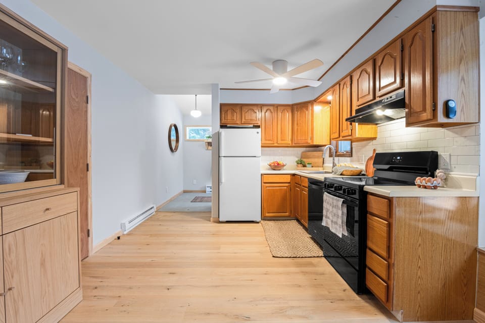 Bright, fully equipped kitchen with warm wood cabinetry, modern appliances, and a sunny window—perfect for easy meals and cozy mornings in.