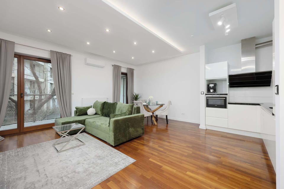 Elegant living room with a green sofa, stylish decor, and bright natural light.