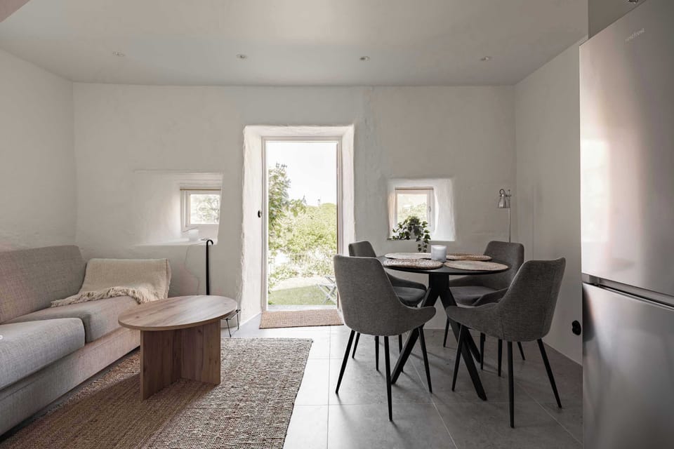 View towards the living room with a cozy seating area. The sofa can be converted into a bed (120 cm wide) for one additional guests.