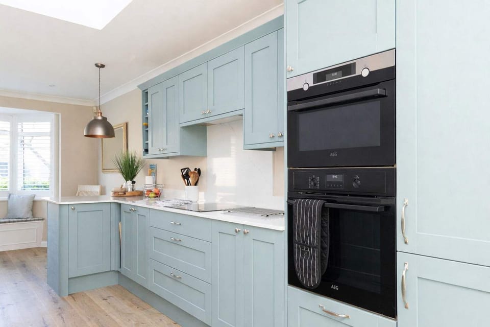 With gorgeous modern cabinetry in calming sea tones and sleek quartz worktops.