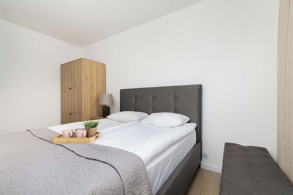 A bedroom perspective showing the bed from the side with soft lighting. Neutral colors create a calm atmosphere. The room looks well-maintained.