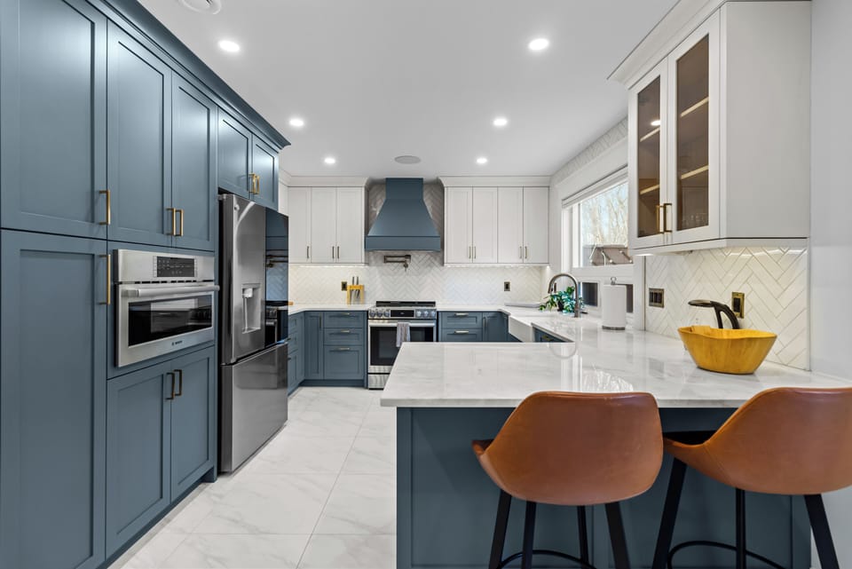 Gourmet kitchen with striking blue cabinetry, a sprawling white quartz island, and top-of-the-line stainless steel appliances.