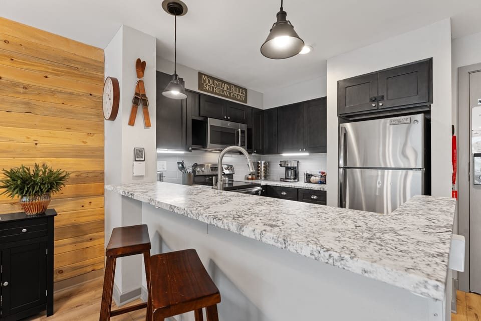 Your fully equipped kitchen features granite countertops, stainless steel appliances, and a breakfast bar where you can enjoy your morning coffee or prep meals with plenty of workspace.