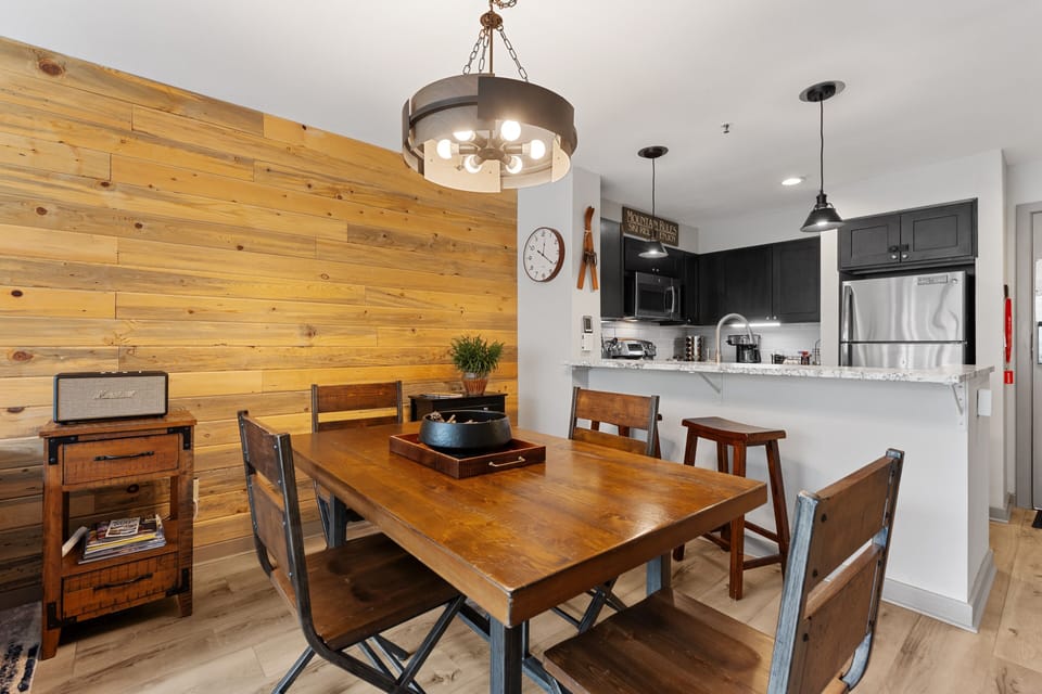 Gather around your rustic wood dining table under warm pendant lighting, with a fully equipped modern kitchen just steps away for easy meal prep and entertaining.