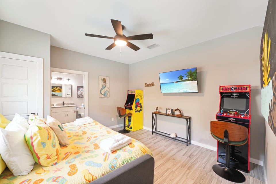 Unwind in your game room featuring retro arcade machines, tropical TV scenes, and cozy seating for endless entertainment.