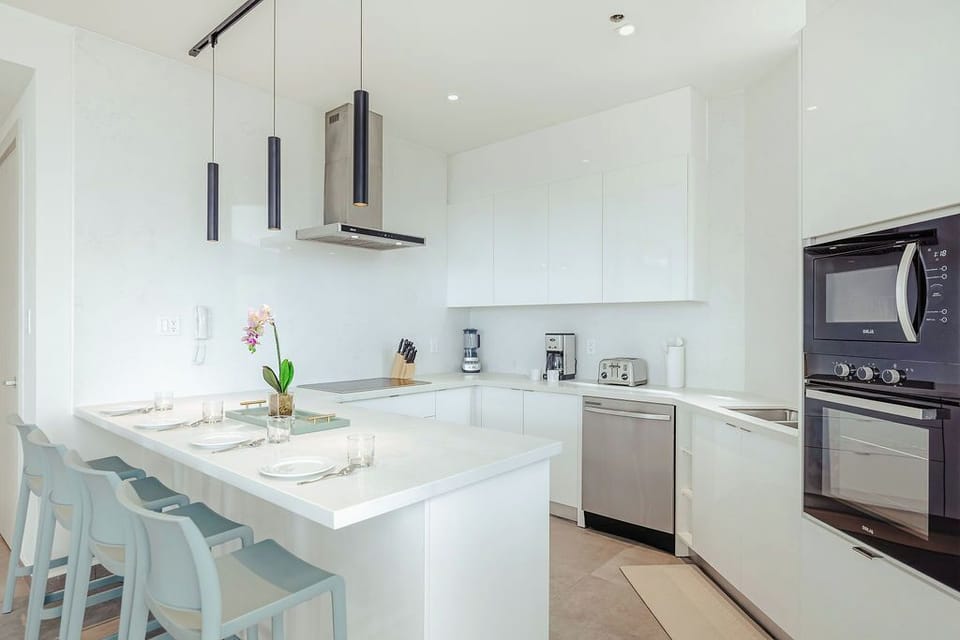 Your bright, modern kitchen awaits with sleek white cabinetry, stainless appliances, and a breakfast island where you can sip morning coffee in style.