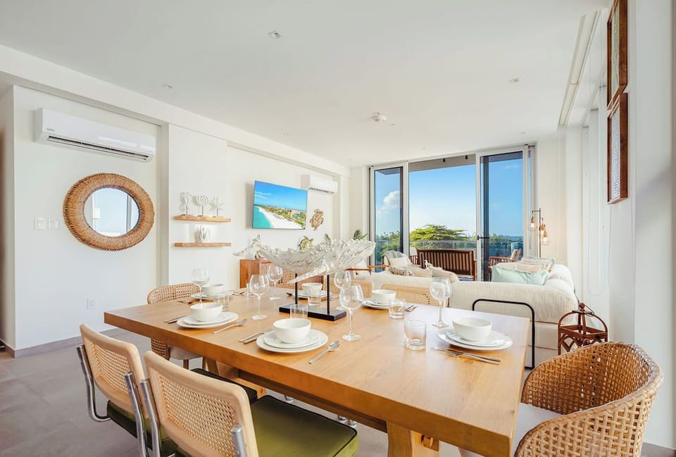 Gather around this sun-filled dining space where coastal breezes and ocean views create the perfect backdrop for your meals. The open layout flows seamlessly to the living area, making every moment feel effortlessly relaxed.
