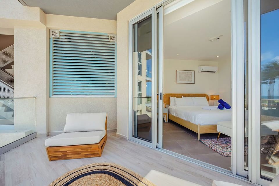 Step from your private balcony into a serene bedroom where ocean breezes meet modern comfort. Fresh linens, soothing blues, and sleek design create your perfect coastal escape.