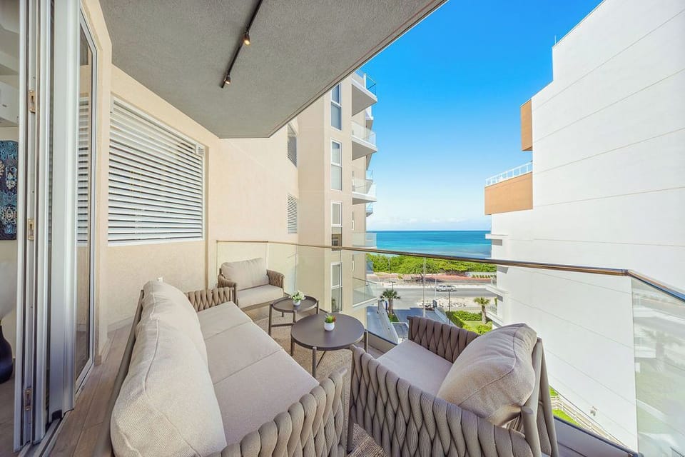 Stylish covered balcony with plush seating and partial ocean views—ideal for morning coffee or evening relaxation in your private outdoor retreat.