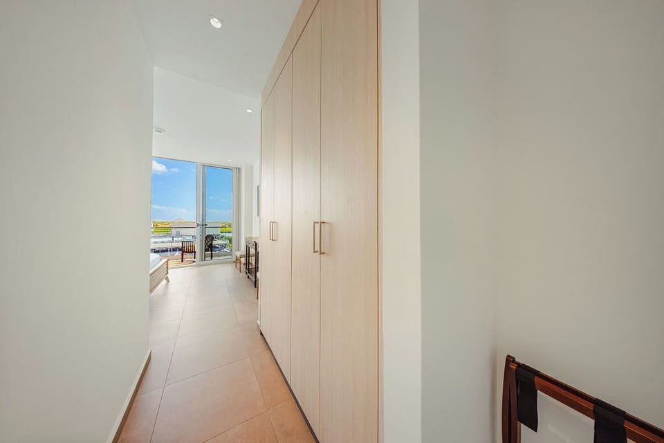 A bright hallway greets you with clean lines and built-in storage, leading to a sun-drenched balcony overlooking the water—your perfect retreat awaits.