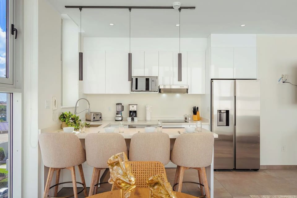Gather around the sleek breakfast bar where modern style meets comfort—your mornings start with fresh coffee and natural light flooding this bright, open kitchen.