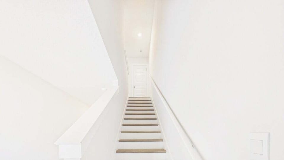 Elegant wooden stairs lead you to your private upper level, bathed in natural light from the skylight above.