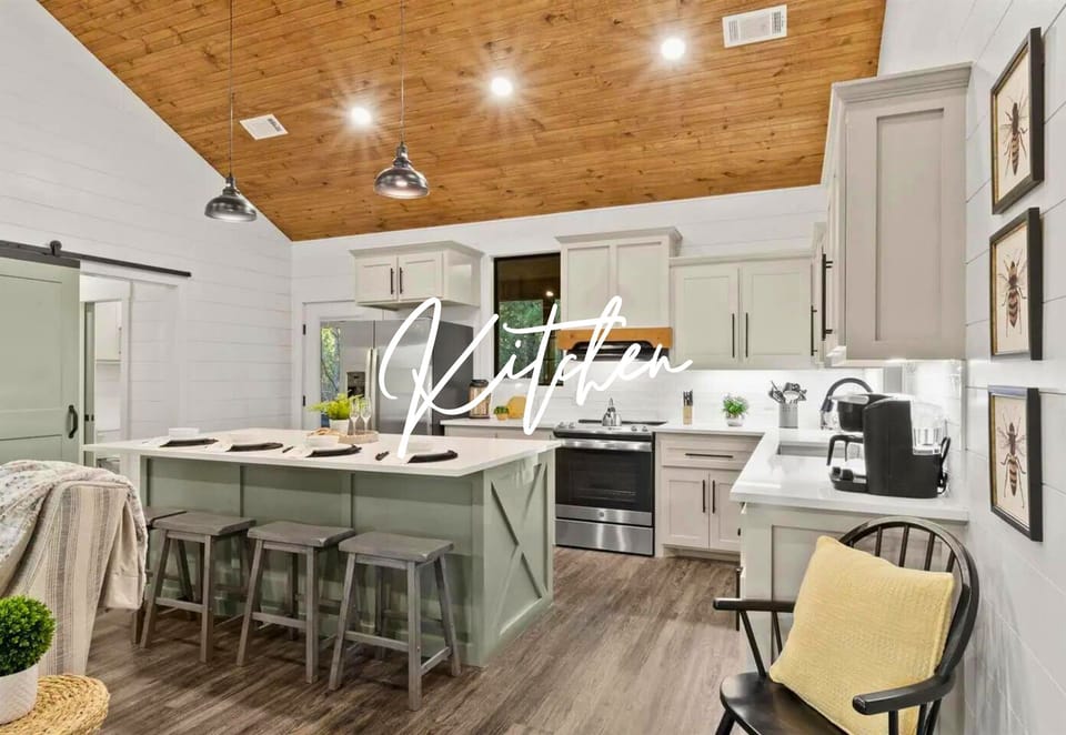 Your spacious kitchen features modern appliances, a welcoming island with bar seating, and warm wood ceiling that creates the perfect gathering space.
