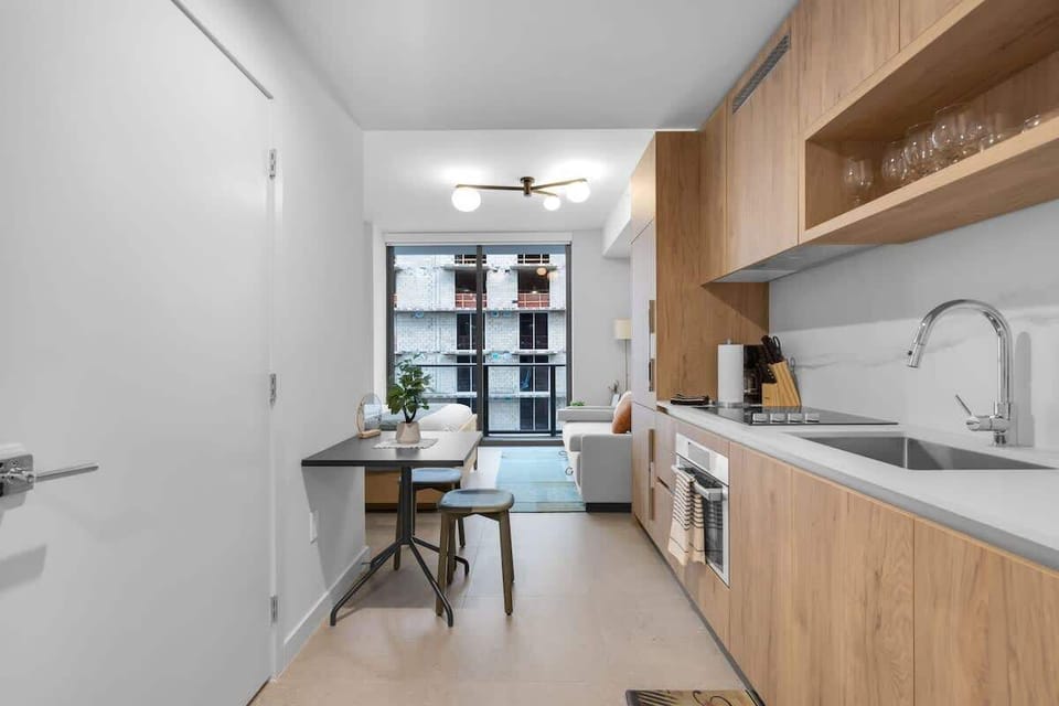 This view from the entrance shows the seamless layout of the studio. To your right, a fully equipped modern kitchen; to your left, a dining table for two; and straight ahead, your relaxing living space.