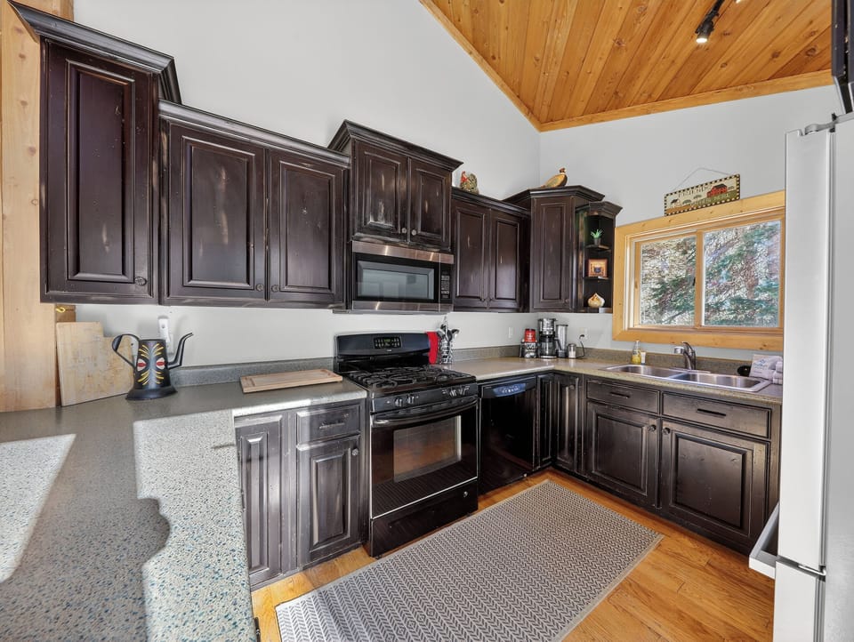 Your fully equipped kitchen awaits with dark cabinetry, modern appliances, and warm wood accents for memorable meals.