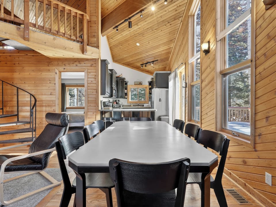Your dining space features soaring wood ceilings and floor-to-ceiling windows that flood the room with natural light and forest views.