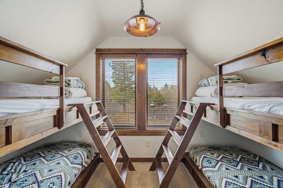 Your cozy bunk room features handcrafted wooden beds with soft linens, perfect for family adventures under warm pendant lighting.